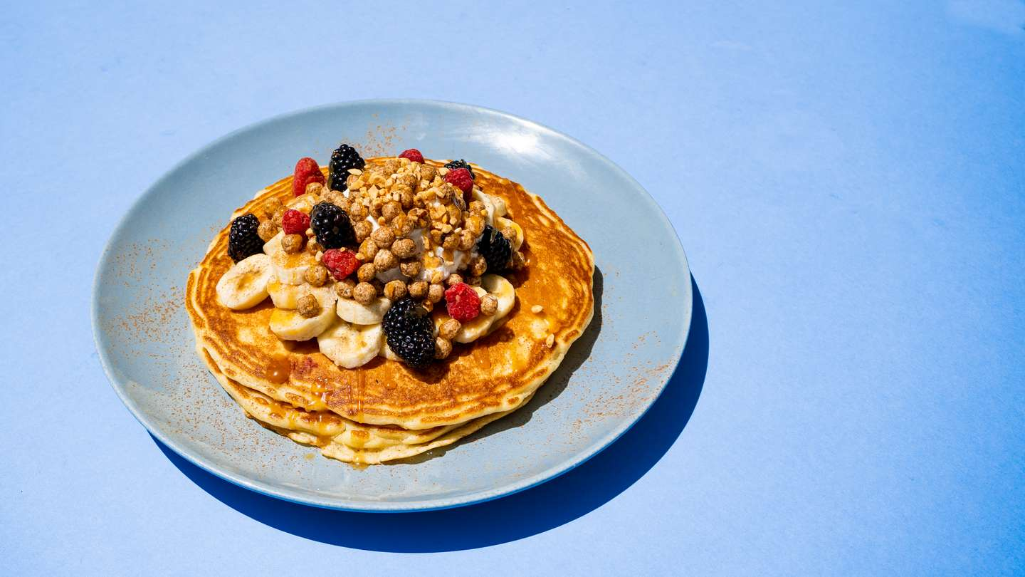 Two Pancakes topped with Cinnamon Cereal, whipped Cream, Bananas, Caramel and fresh berries.